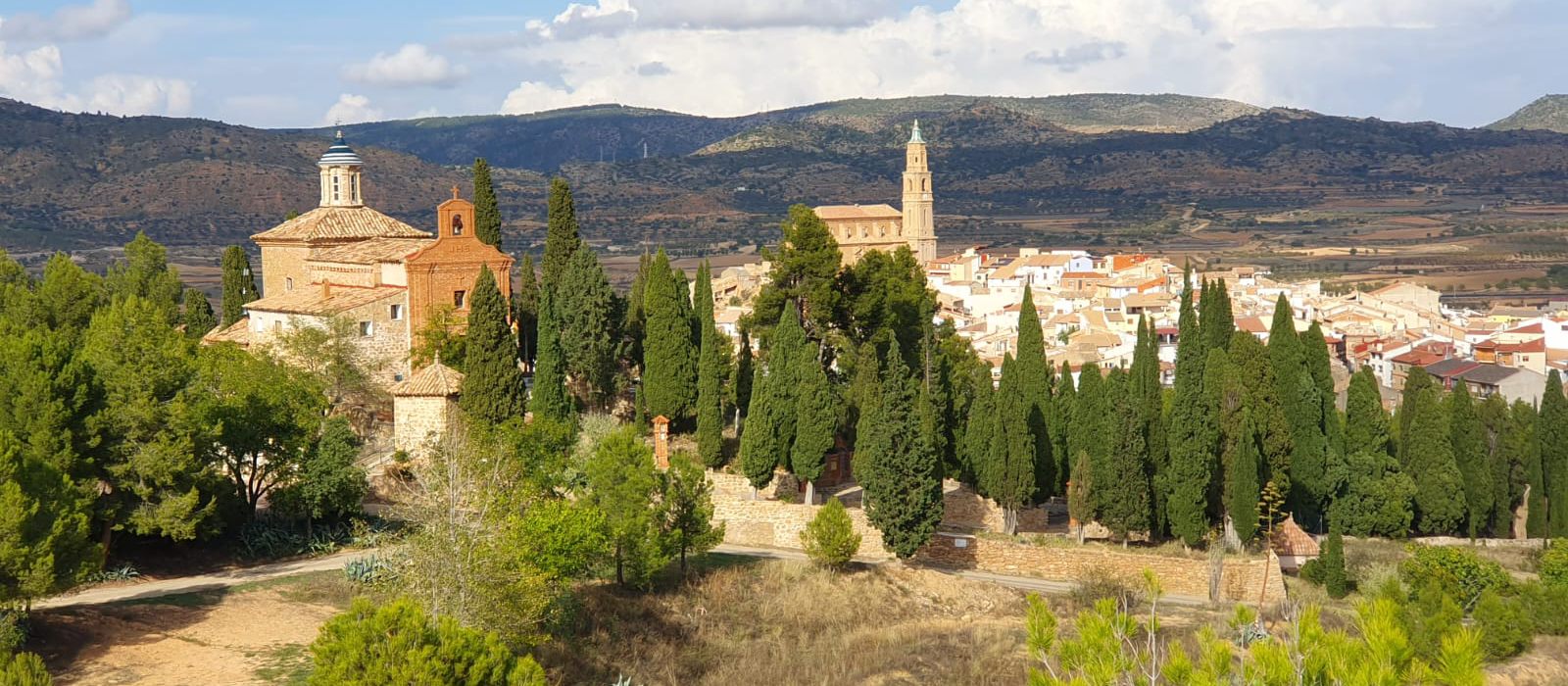 Alloza visto desde fuera: la ermita del calvario, la torre de la iglesia y la sierra al fondo